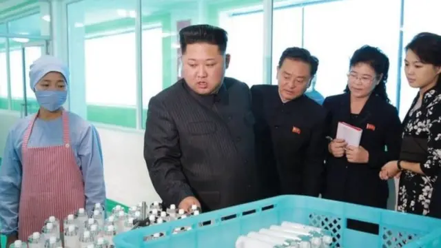 Kim Jong Un holds clear liquid samples in bottles at factory visit