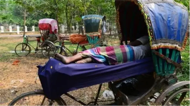 প্রচণ্ড গরমে কাজ বন্ধ রেখে বিশ্রাম নিচ্ছেন একজন রিক্সাচালক