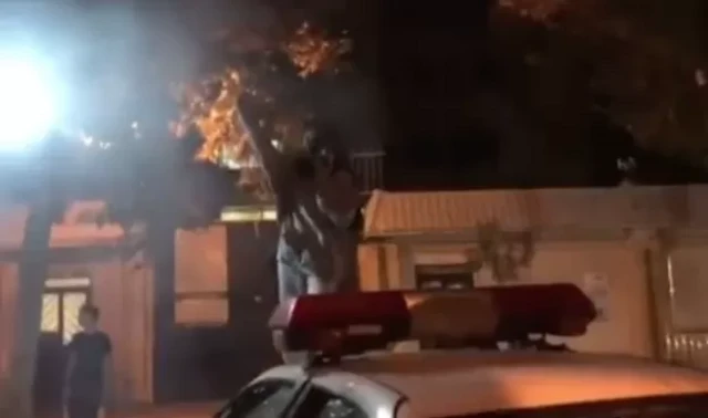 صورة من مقطع فيديو تظهر فيه امرأة في مشهد أمام مقر محكمة الثورة وهي تهتف فوق سيارة للشرطة.