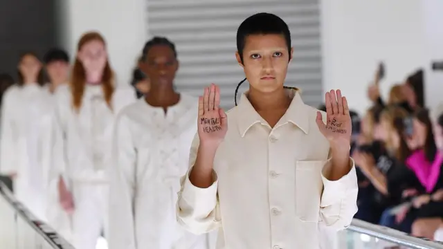 Ayesha Tan-Jones protestou no meio do desfile com uma mensagem escrita na palma das mãos