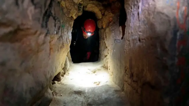 Hombre atravesando un túnel en las catacumbas de París.