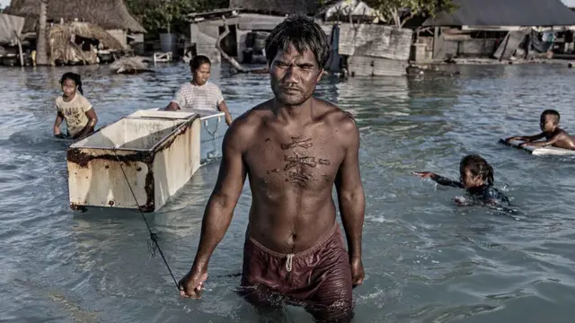 Populaçãouniformes de futebolKiribati sendo afetada por inundação