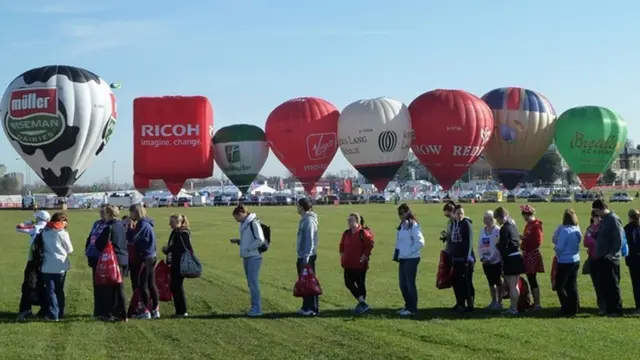 أشخاص ينتظرون في طابور بالقرب من مناطيد هوائية