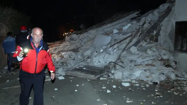 People walk past rubble as rescue operations begin in Villa Sant'Antonio village, near Visso, Marche region, Italy, on 26 October 2016