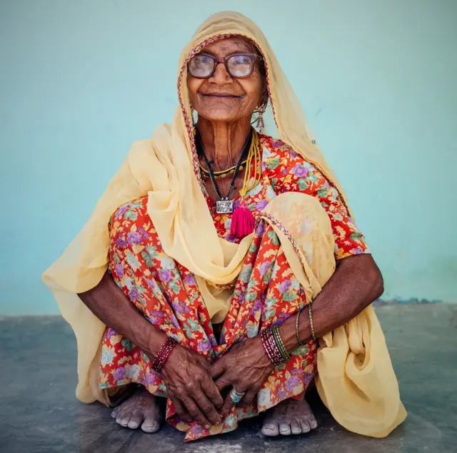 Anciana india sentada en cuclillas.