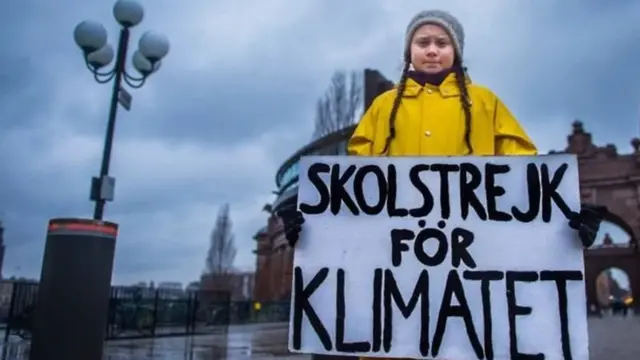 Greta Thunberg with a sign saying "school strike for the climate" in Swedish