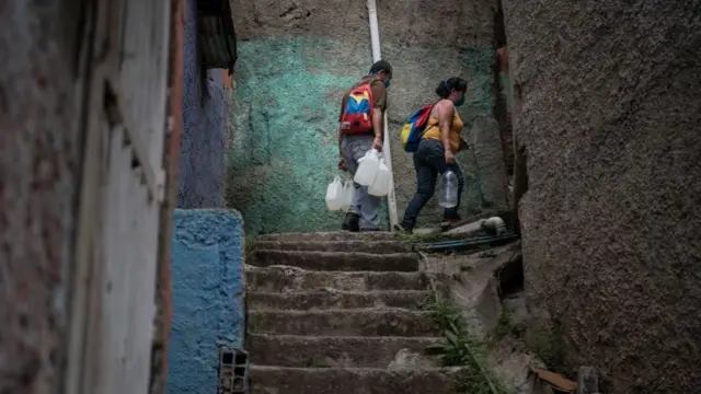 Dos personas llevan agua en envases de plástico