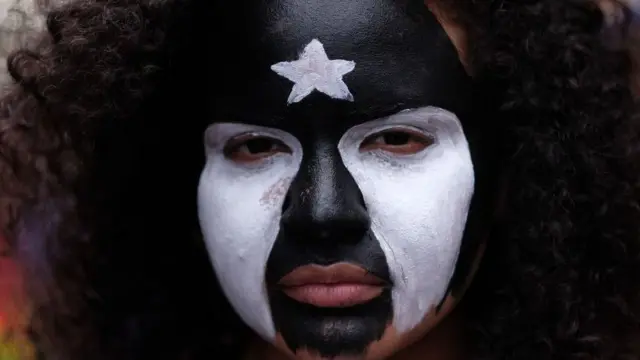 Una mujer con la cara pintada con la bandera de Puerto Rico en blanco y negro protesta contra los recortes de las pensiones y el cierre de escuelas el 1 de mayo de 2018 en San Juan.