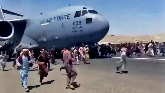 Gente corre en la pista del aeropuerto de Kabul tratando de abordar un avión de la Fuerza Aérea de EE.UU.
