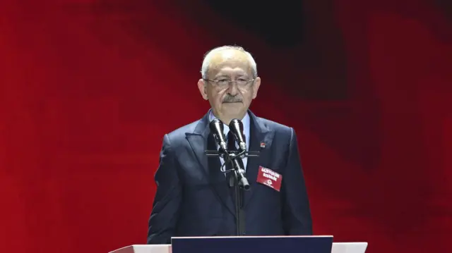 Kemal Kılıçdaroğlu genel başkanlığı kaybettiği 38. Kurultay'da konuşma yapıyor. Arkasında kırmızı bir fon var. Ayakta duruyor.
