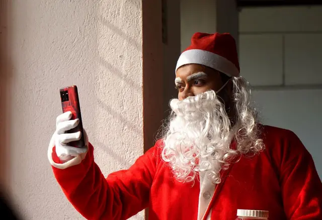 Wani matashi ya yi shigar Father Chrismas yana ɗaukar hoto da waya.