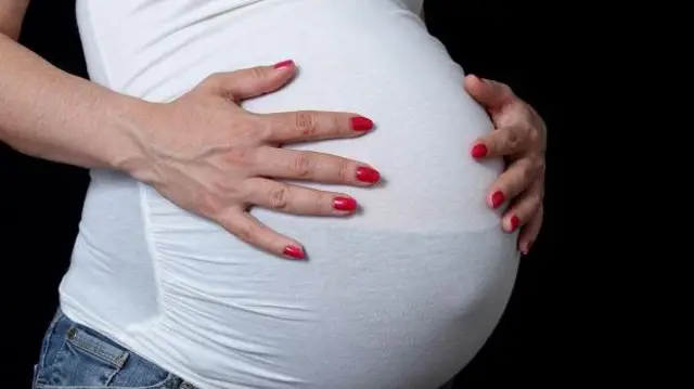 امرأة حامل تضع يديها على بطنها