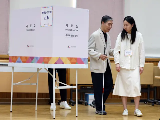 서울 종로구 무악동주민센터에 마련된 사전투표소에서 시각장애인 유권자가 사전투표사무원의 도움을 받으며 투표를 하고 있다