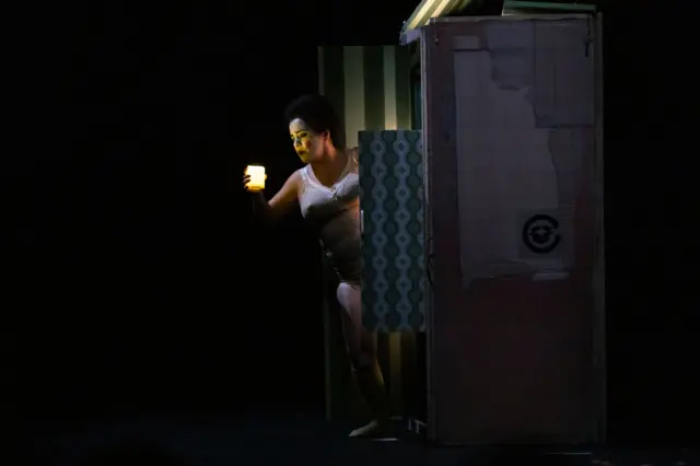 El personaje de Chula, vestida en ropa interior, sostiene una vela encendida