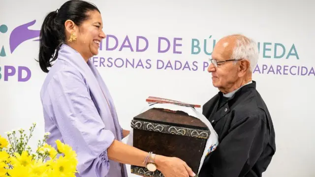 Luz Janeth Forero, directora de la UBPD, entrega los restos al sacerdote jesuita, Javier Giraldo.