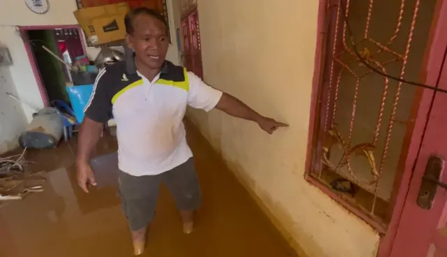 Pria kelahiran 1971 menunjukkan tinggi banjir di dalam rumahnya.