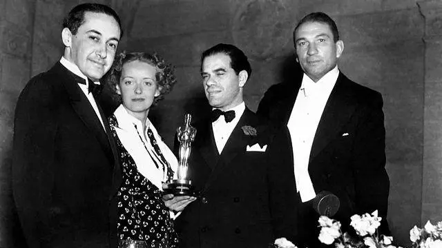 Bette Davis com o Oscar de melhor atriz de 1935, rodeada por três homens em foto em preto e branco