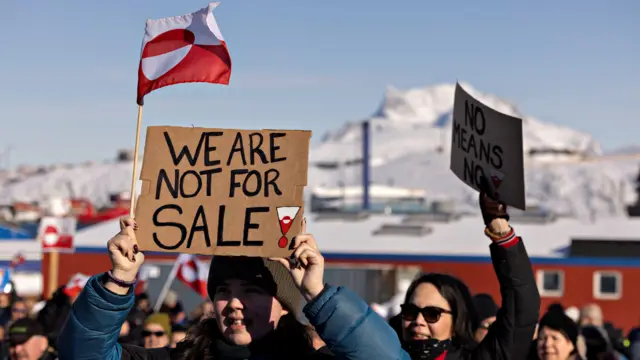 Manifestantes reunidos em frente ao consulado americano na capital da Groenlândia, Nuuk, no dia 15 de março de 2025. "Não estamos à venda", diz o cartaz em inglês.