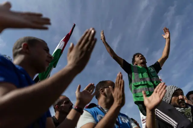Voluntarios y personal de ONG celebran el paso de camiones ayuda en la frontera de Rafah desde Egipto.