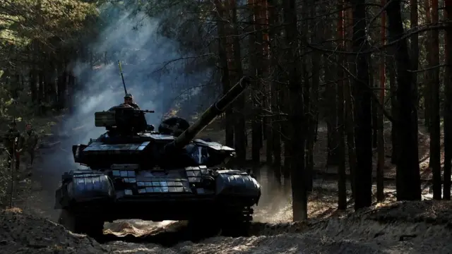 Ukrainian soldiers drive a captured Russian tank in Kupiansk region