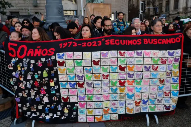 Grupo segura cartaz com os dizeres "seguimos buscando"