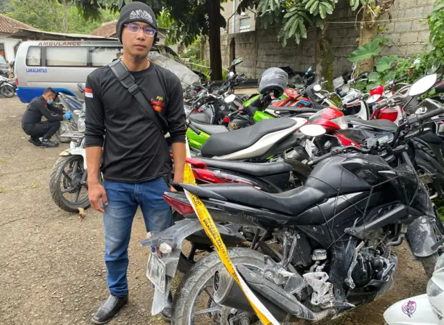 Ilham Abdilah di sebelah sepeda motornya yang mati total akibat terkena soda api di Bandung Barat.
