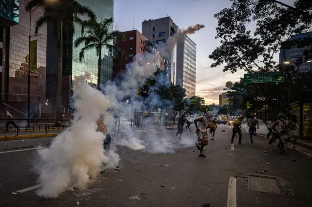 Rua5.5 1xbetCaracas com manifestantes fugindo e lançando bomba5.5 1xbetgás lacrimogêneo