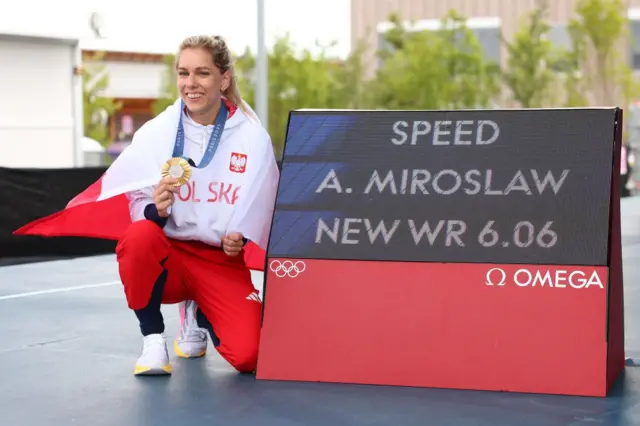 Aleksandra Miroslaw señalando el cartel donde dice su récord: 6,06 segundos