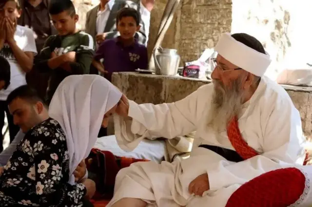 الشيخ الإيزيدي الكبير" يبارك امرأة في "عيد ئيزي" بعد ثلاثة أيام من الصيام. أكتوبر/تشرين الأول 2017 في معبد لالش بإقليم كردستان العراق