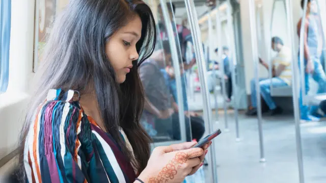 मेट्रो में फ़ोन देखती एक युवती