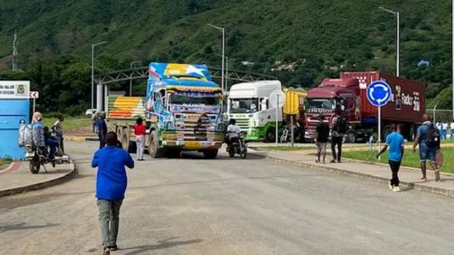 Kamyo zitatu, imwe y'irangi ry'umuhondo, iry'urwatsi rutoto n'iryera ahagaze ku rubibe rwa Tanzania na Malawi mu gihe abashoferi n'abadandaza bariko bararengana. 