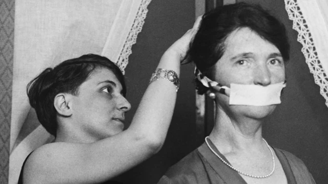A woman fastens a mask to Margaret Sanger's face in Boston on 17 April 1929