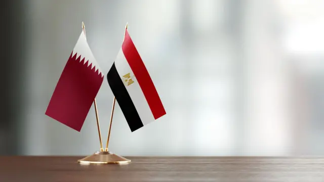 علمان قطري ومصري على مكتب على خلفية غير واضحة - صورة فوتوغرافية