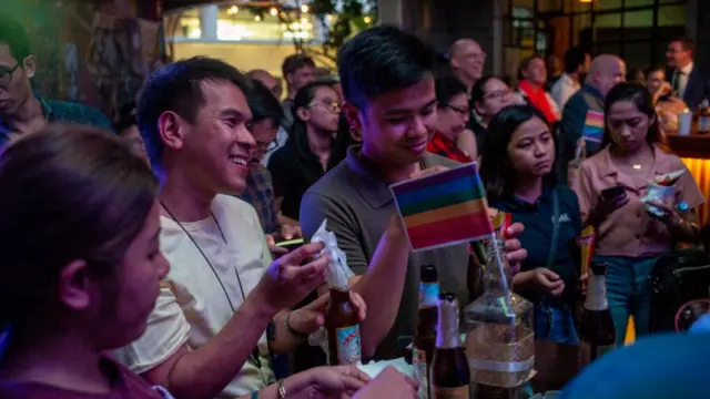 Pessoasbar tomam cerveja, com bandeira do arco-íris decorando mesa