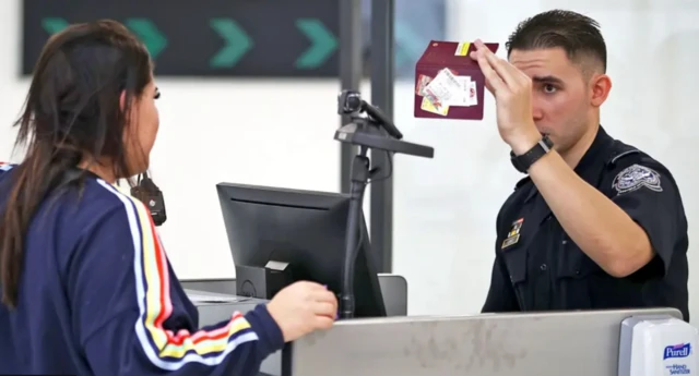 ABD sınır polisi, bir turistin pasaportunu kontrol ediyor. Kadın karşıdan polise bakıyor