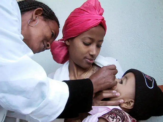 ሓኪም ኣብ ሕቝፊ ኣደኣ ንዘላ ህጻን ክታበት እናሃበታ
