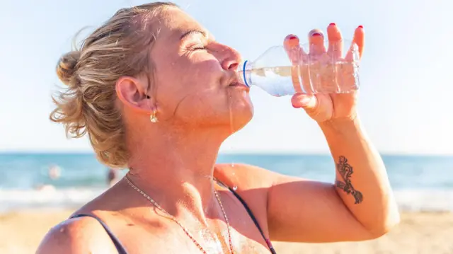 Mujer bebiendo agua de una botella.