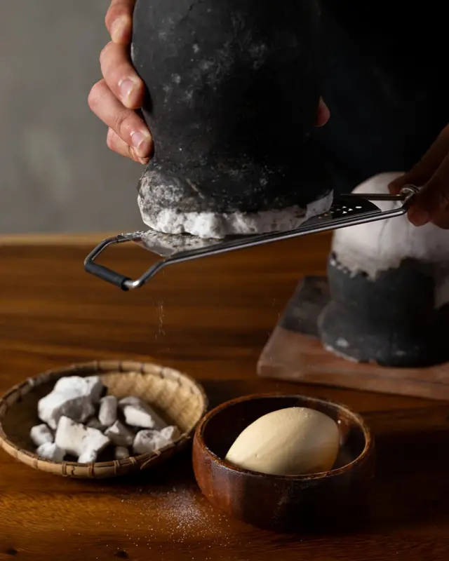 Людина натирає великий шматок солі на терці