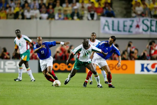 Les Français Sylvain Wiltord (à gauche) et Youri Djorkaeff exercent un pressing conjoint sur le Sénégalais Papa Bouba Diop durant la première mi-temps du match du groupe A de la phase de poules de la Coupe du monde opposant la France au Sénégal, disputé au stade de la Coupe du monde de Séoul (Corée du Sud) le 31 mai 2002. 