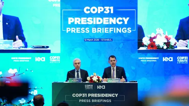 Kurum ve Fatih Birol COP31 Presidency Press Briefings yazılı kürsüde oturuyor. Arkalarındaki ekran da da aynı yazılar ve görüntüleri yansıtılıyor. 