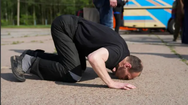 Український військовий цілує землю після повернення з російського полону 