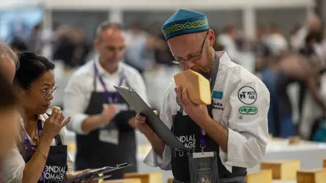 Чоловік нюхає шматок головки сиру під час конкурсу