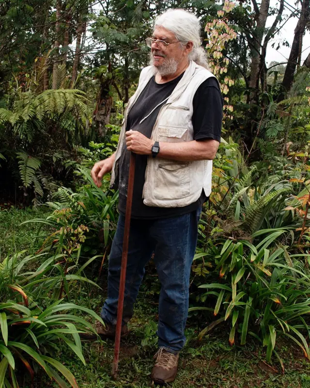 Um homem branco com cabelos grisalhos, numa floresta