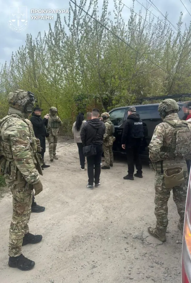 Люди у військовій формі біля темного автомобіля