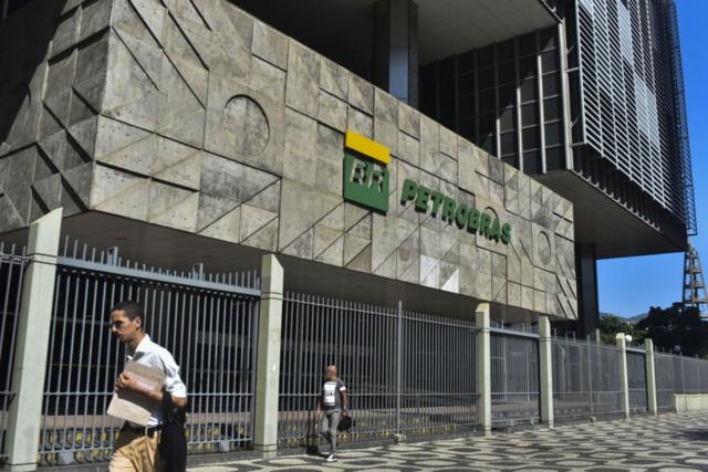 Dois homens na calada passando em frente  sede da Petrobras