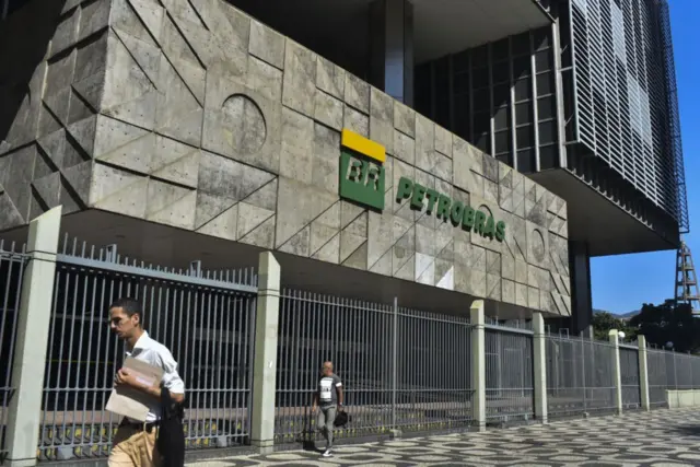 Dois homens na calçada passandobetspeed nao deixa sacarfrente à sede da Petrobras