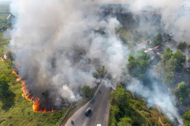 Foto udara sejumlah pengendara melintas di Jalan Lintas Timur (Jalintim) Palembang-Prabumulih saat kebakaran lahan terjadi di Desa Sungai Rambutan, Indralaya Utara, Ogan Ilir (OI), Sumatera Selatan, Sabtu (8/8/2026). Petugas gabungan dari Manggala Agni Sumatera XIV-Banyuasin, Sumatera XVI-Lahat, BPBD Provinsi Sumatera Selatan, BPBD Kabupaten Ogan Ilir (OI), TNI, dan Polri masih berupaya memadamkan kebakaran lahan di Jalintim Palembang-Prabumulih. 