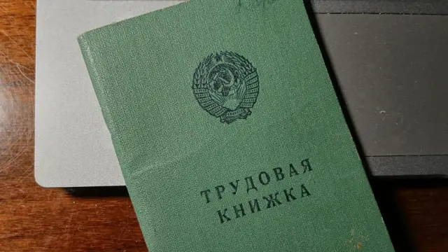 Трудова книжка радянського зразка лежить на клавіатурі ноутбука.