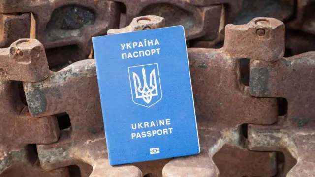 «Оккупированный Донецк не нужен никому». Как молодежь ждет совершеннолетия, чтобы уехать из оккупации в «свободную Украину» 6 Загранпаспорт гражданина Украины виден на фоне уничтоженной российской военной техники на Михайловской площади в Киеве