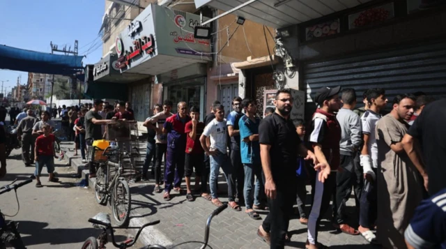 Warga Palestina menunggu untuk membeli roti setelah Israel membatasi area layanan dasar seperti air, listrik, dan makanan di Khan Younis.